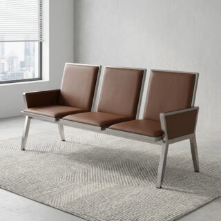 A three-seat tandem waiting room bench featuring camel brown leather cushions, integrated armrests, and a brushed silver metal frame on a grey carpeted office floor.