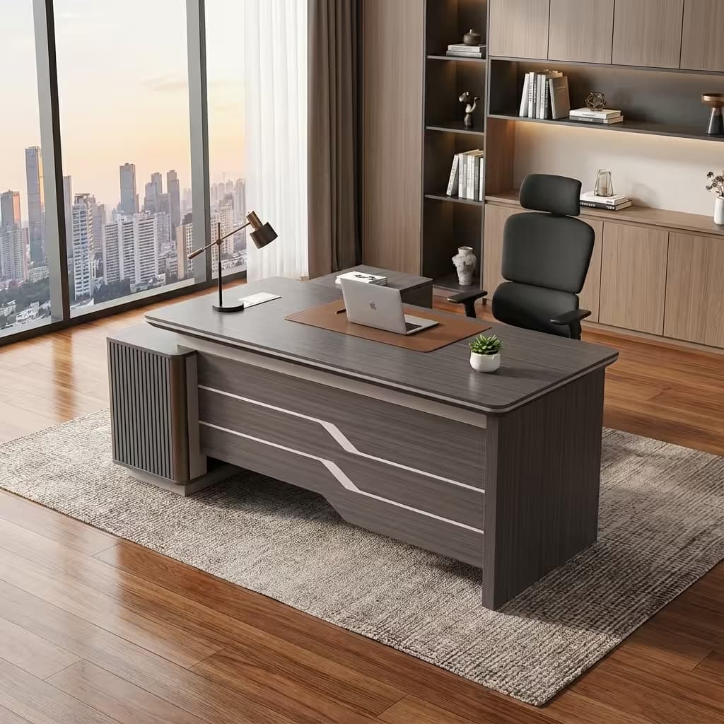 A grey wood grain 1.6m Executive Office Desk featuring a curved-edge tabletop, a brown leather writing insert, a front modesty panel with silver stripe accents, and an integrated side return cabinet with vertical fluting.